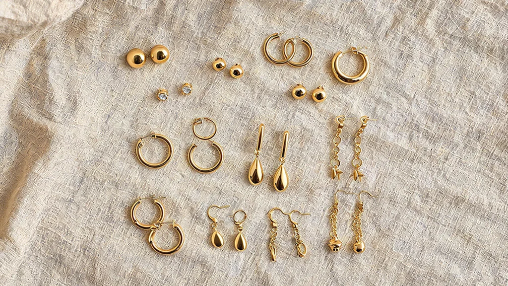Flat lay of different types of earrings including studs, hoops, and drops