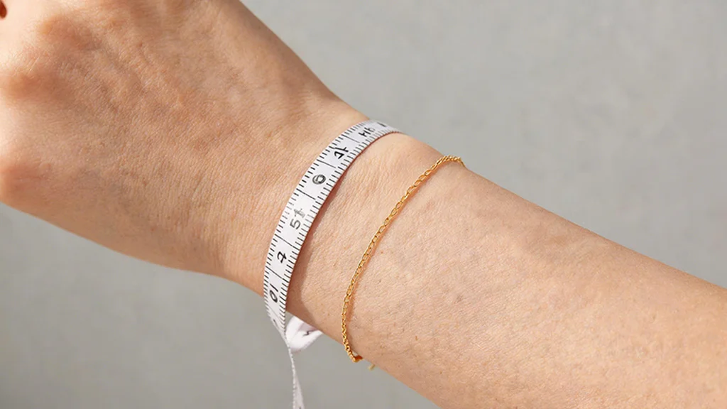 Woman measuring her wrist with a flexible tape for bracelet sizing